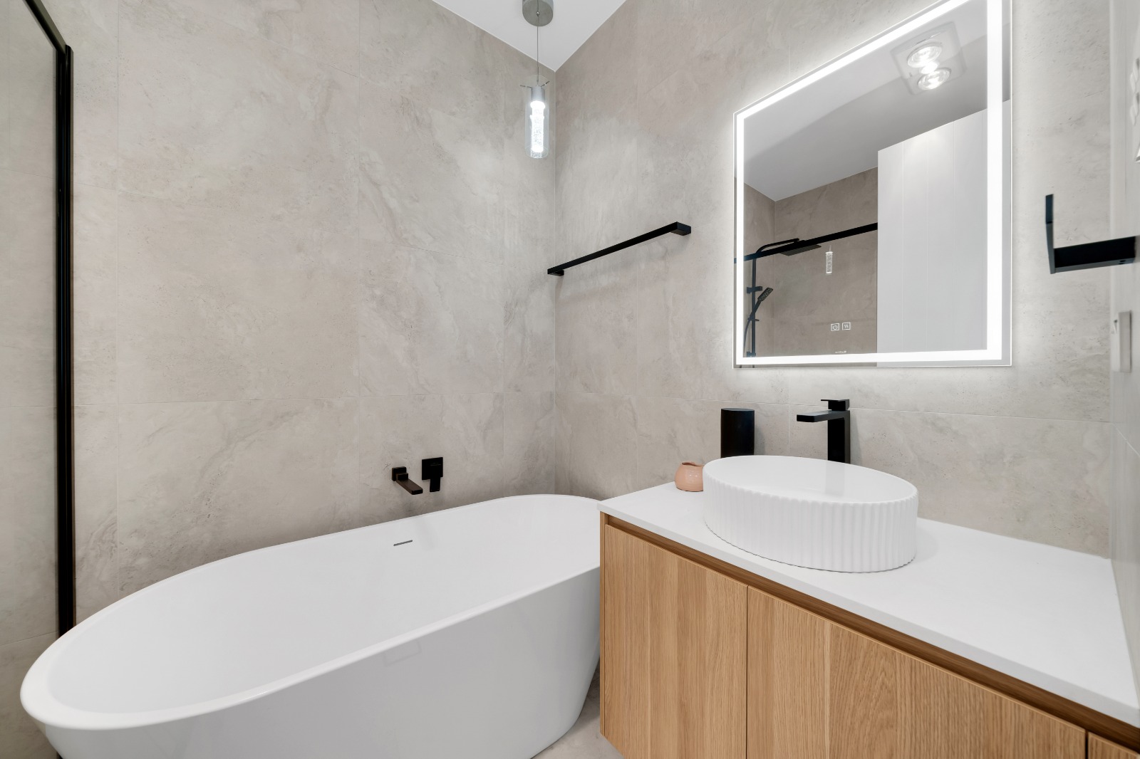Bathroom with freestanding bath, backlit mirror and timber vanity