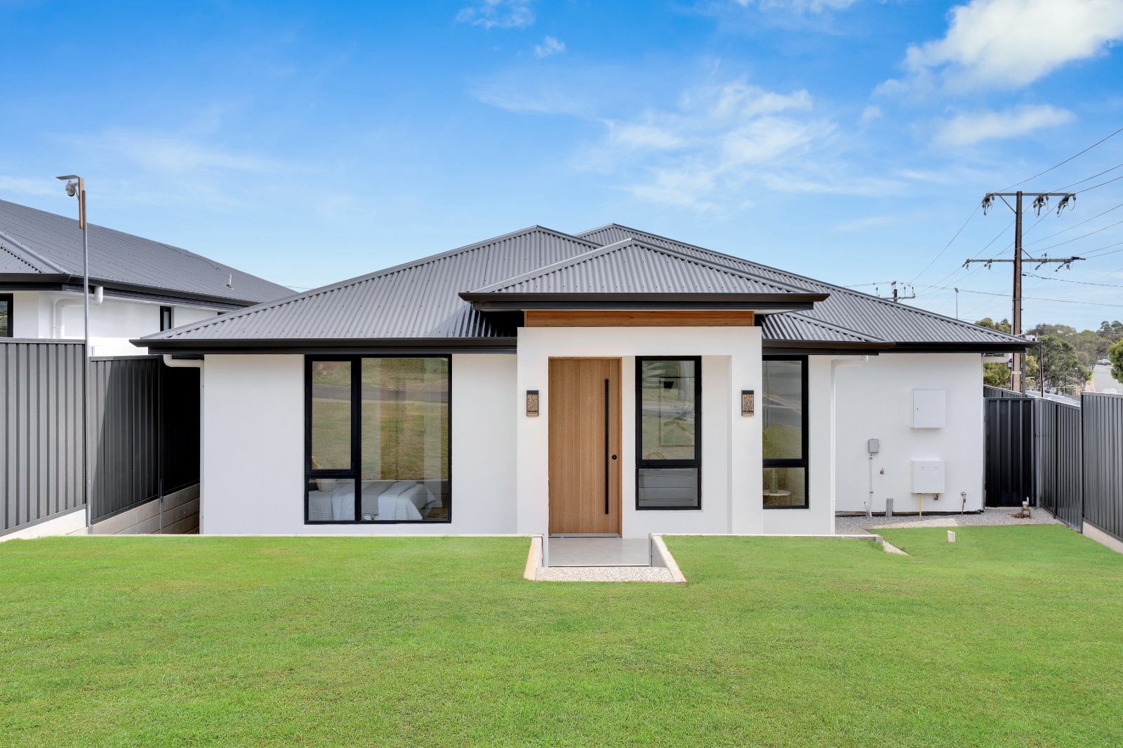 Completed single-storey rendered home at Ingle Farm with a timber front door and black-framed windows